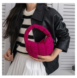 Gros plan d'un sac nuage matelassé fuchsia montrant la texture bouffante et la fermeture