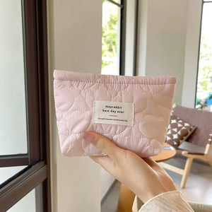 Detail of pink heart-quilted pouch with fabric label and soft lifestyle texture