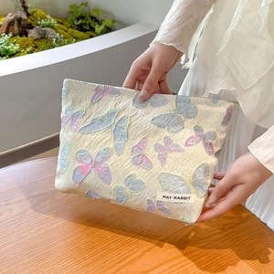 Detail of floral jacquard makeup bag featuring May Rabbit label and butterfly embroidery