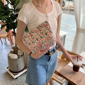 Floral makeup bag featuring pink tulip prints and brand label in a cafe setting