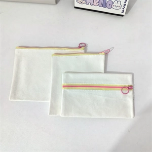 Three-piece set of white canvas pouches with yellow zippers and pink ring pulls for storage