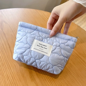 Detail of light blue quilted bear makeup bag featuring heart patterns and premium zipper