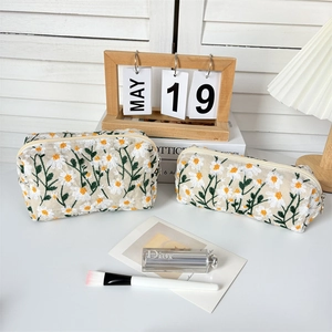 Detail of canvas makeup bag set featuring delicate daisy embroidery and organized storage