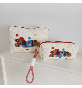 Detail of heart-quilted pouch set with 3D puppy embroidery and colorful pom-poms