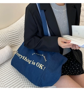 Detail der blauen Denim-Tasche mit Everything is OK Text und langen Schultergurten