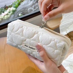 Close-up of white quilted pencil case with cloud stitching and metal ring zipper pull
