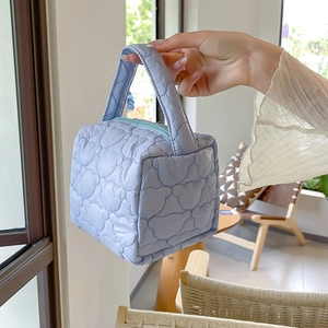 Detail of light blue quilted makeup bag with bear patterns and secure zipper closure