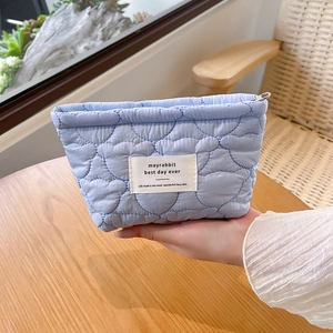 Detailed view of blue heart quilted cosmetic bag showing soft fabric texture and label