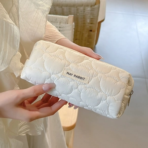 Detailed view of quilted heart texture on beige soft pencil case and fabric label