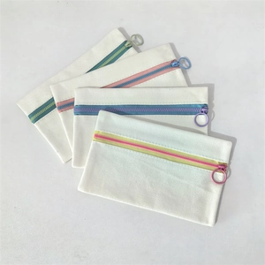 Detail of four canvas pouches with colorful zippers and large circular zipper pulls