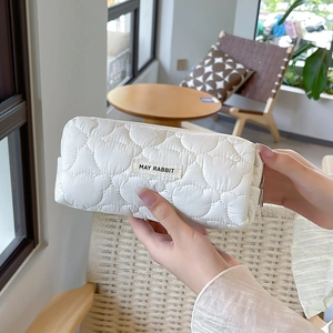 Close-up of white heart-quilted stationery pouch with MAY RABBIT label and zipper