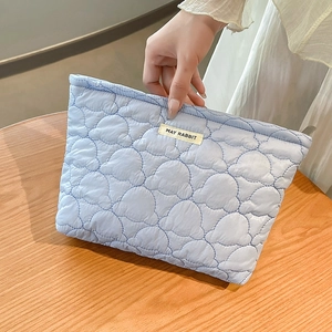 Close-up of light blue quilted cosmetic bag with cloud texture and MAY RABBIT label