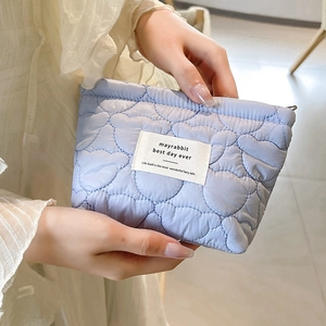 Detailed heart-quilted texture on a light blue pouch with a white woven label