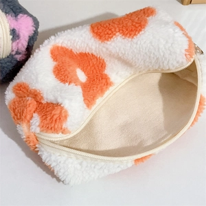 Detail of plush white fleece pouch featuring orange floral patterns and metal zipper