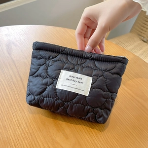 Detailed view of black quilted pouch with heart patterns on a wooden table surface
