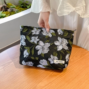Detail of black floral jacquard makeup bag with May Rabbit label and embroidery