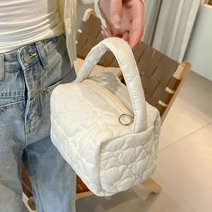 Detail of white quilted handbag with heart patterns and metallic ring zipper