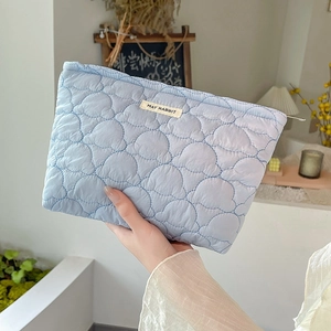 Quilted light blue makeup bag with May Rabbit label shown in a hand-held lifestyle setting
