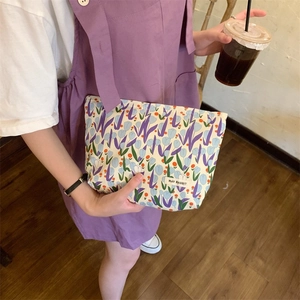Detailed close-up of a purple tulip floral canvas makeup bag with a woven brand label