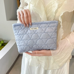 Close-up of light blue quilted makeup bag with cloud pattern and soft textile texture