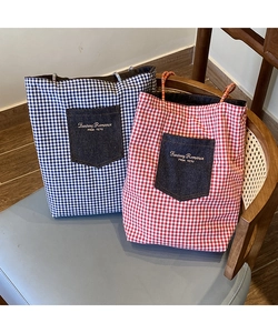 Dettaglio della borsa tote in tela a quadretti rossi e blu con tasca in denim ricamata