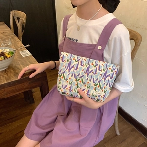 Detail of floral tulip makeup bag with MAY RABBIT tag held by a woman in a cafe