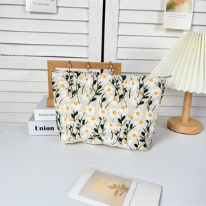 Macro detail of daisy embroidery on a beige linen makeup bag with premium metal zipper
