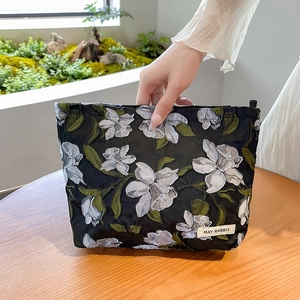Close-up of floral jacquard makeup bag with May Rabbit label and black flower pattern