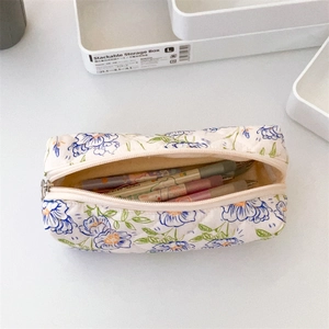 Close-up of quilted floral pencil case with blue flowers and metal zipper closure