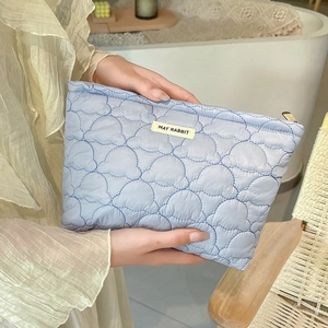Close-up of light blue quilted makeup bag with MAY RABBIT tag and metallic zipper detail