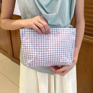 Beauty case a quadri blu con fiocchi rosa e etichetta tenuto da una modella
