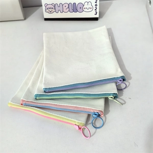 Close-up of four canvas zipper pouches with colorful zippers and metal ring handles