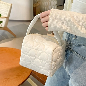 Detail shot of white heart-quilted texture and soft nylon fabric on the puffy tote bag