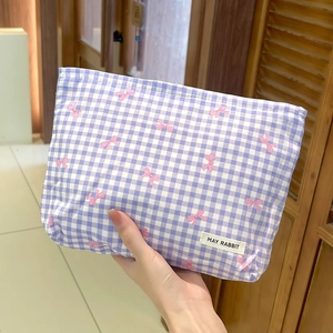 Dettaglio della borsa da trucco a quadri viola con fiocchi rosa ed etichetta tessuta