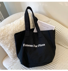 Detail einer schwarzen Segeltuch-Tragetasche mit weißem Famous For Pizza-Aufdruck