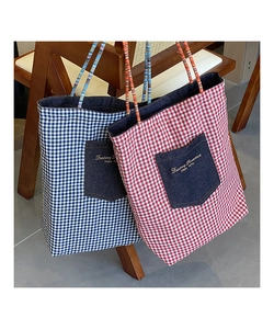 Dettaglio di borse tote in tela a quadretti rossi e blu con tasche in denim e manici intrecciati