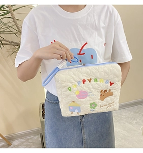 Detail of quilted makeup bag with puppy baby embroidery and blue contrast zipper handle