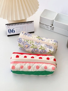 Close-up of quilted floral pencil cases with metal zippers and grid stitching detail