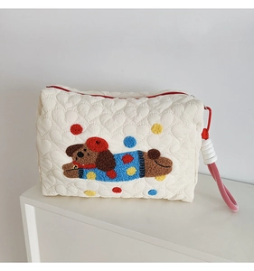 Detail of heart-quilted pouch featuring a chenille puppy embroidery and red handle