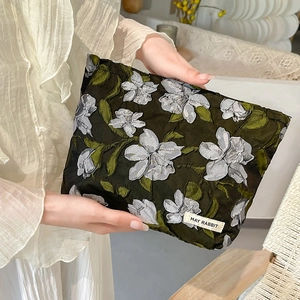 Detail of embossed floral jacquard makeup bag in olive green with fabric brand label