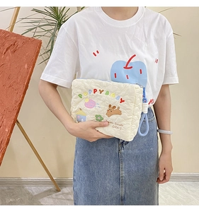 Detail of white quilted cosmetic bag with colorful puppy embroidery and blue handle
