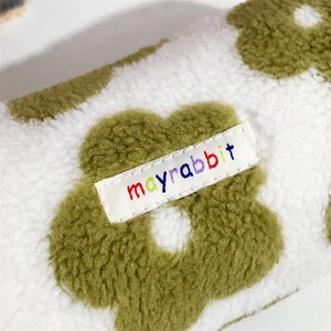 Macro shot of fluffy plush fabric and floral pattern with embroidered brand label