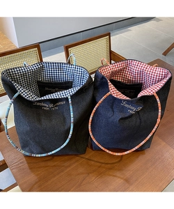 Dettaglio di borse tote in denim con fodera a quadri rossa e blu e ricamo curato
