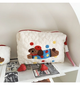 Close-up of quilted cosmetic bag featuring heart stitching and embroidered puppy mascot