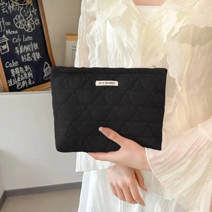 Detail of black quilted makeup bag with bear pattern and May Rabbit brand label