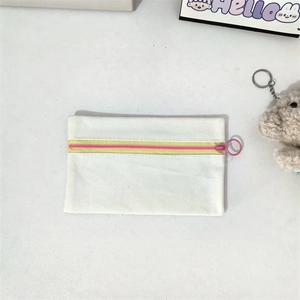 Detailed macro view of cream canvas pouch with vibrant pink and yellow zipper pulls