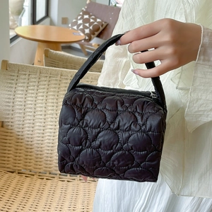 Detail shot of a black quilted puffer handbag with cloud texture and zipper closure