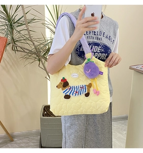 Detail of yellow quilted tote bag with cute dog embroidery and purple eggplant plush charm