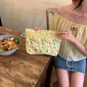 Detail of fabric cosmetic bag with yellow tulip pattern and brand label in hand