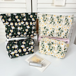 Detail showing embroidered daisy patterns on black and cream travel cosmetic bags